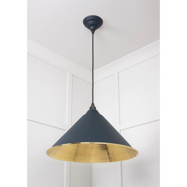 Shade on cone shaped brass and black pendant light, switched off.