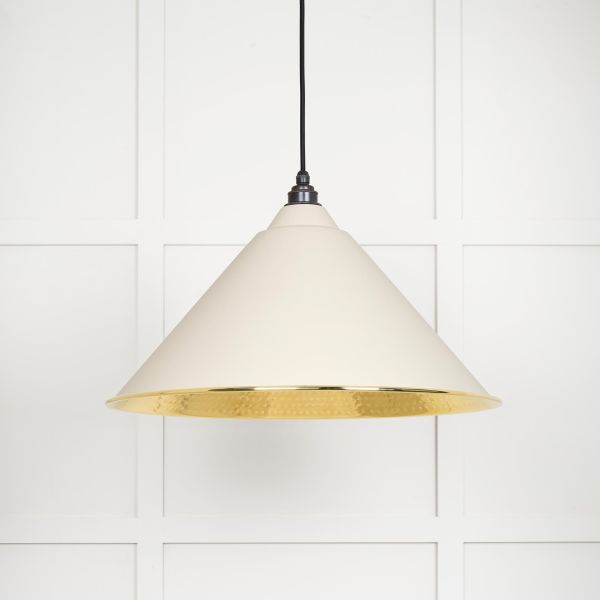 Shade of cone shaped hammered brass pendant light in teasel, switched off.