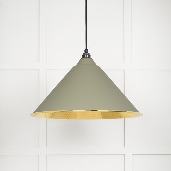 Shade of cone shaped hammered brass pendant light in green, switched off.