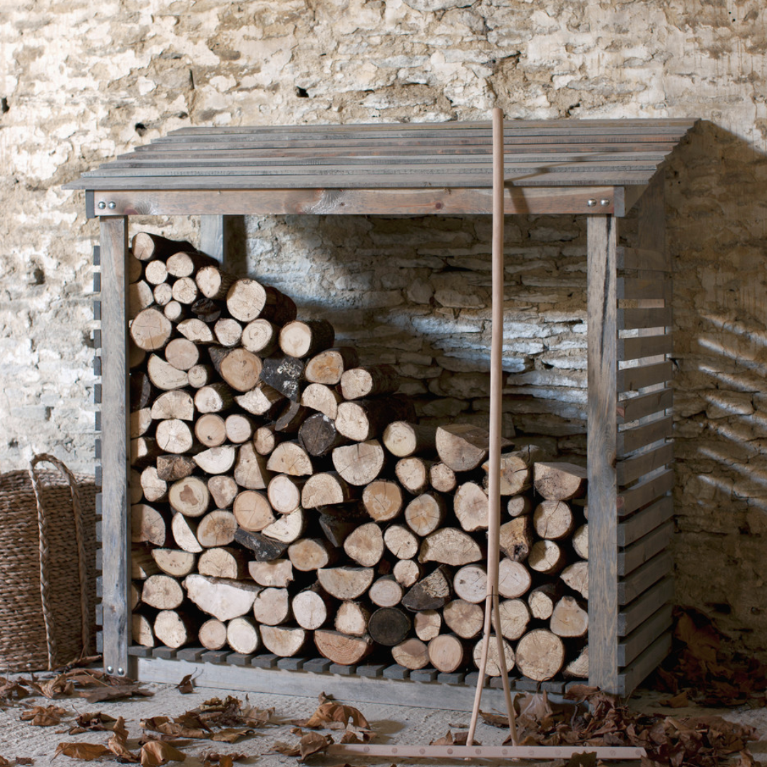 Wide log store full of logs, with autumn leaves.