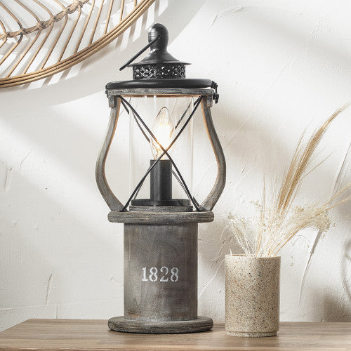 Grey wood table lamp switched on on wooden console table.