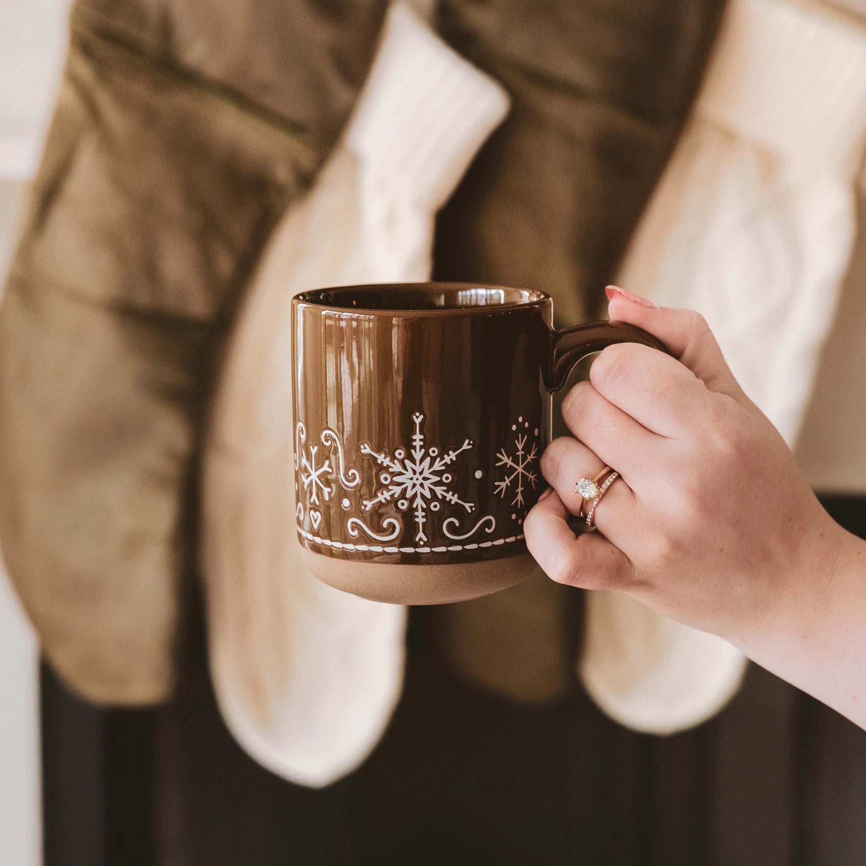 Gingerbread snowflake mug being held up with one hand.