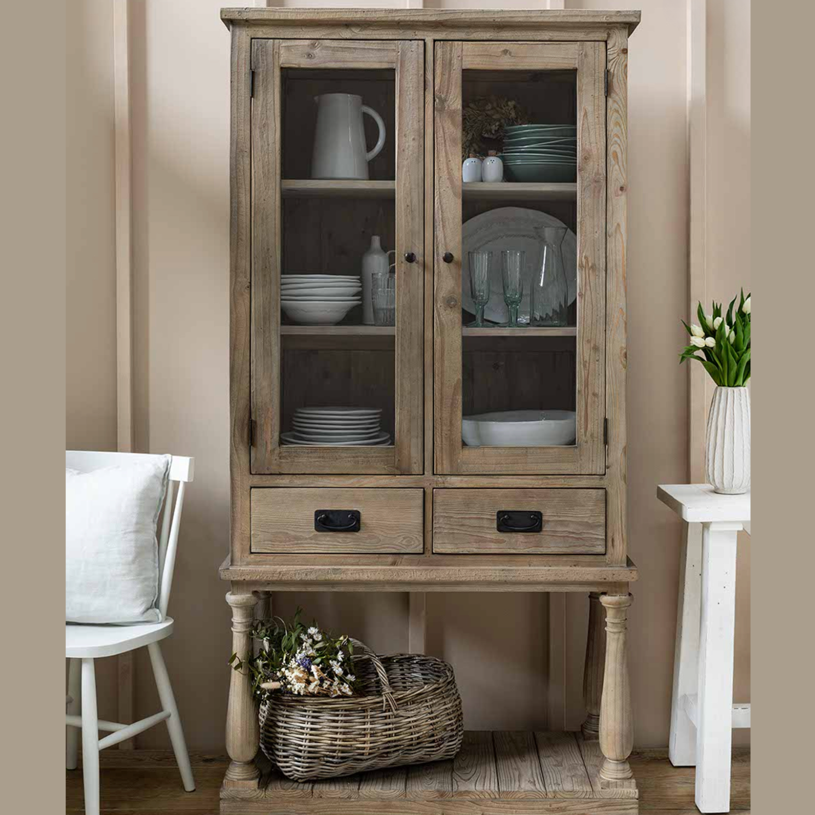 Glass Display Cabinet filled with crockery and a basket of flowers.