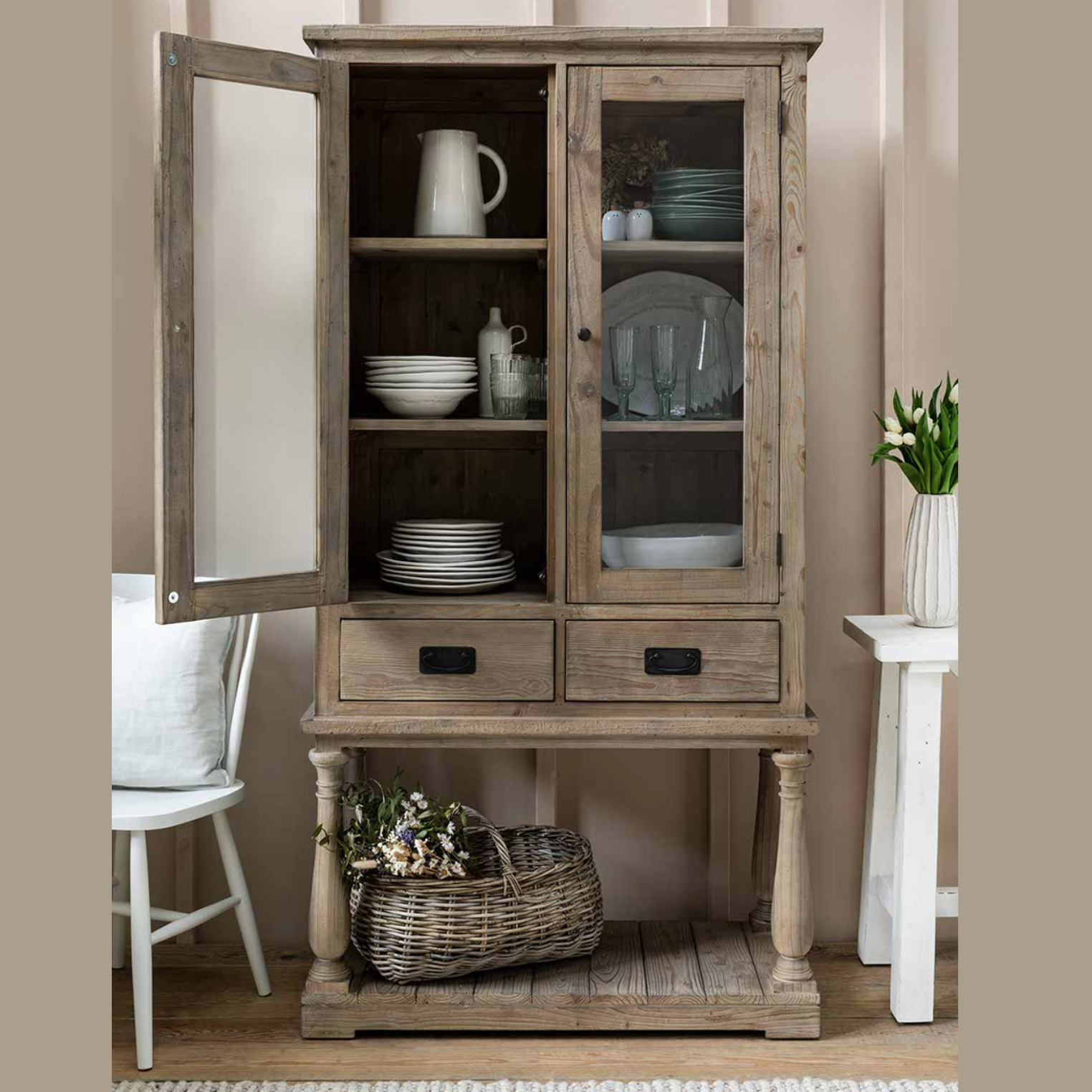 Glass Display Cabinet with crockery and a basket of flowers.