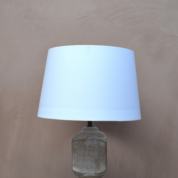 Small white lamp shade on wooden lamp base.