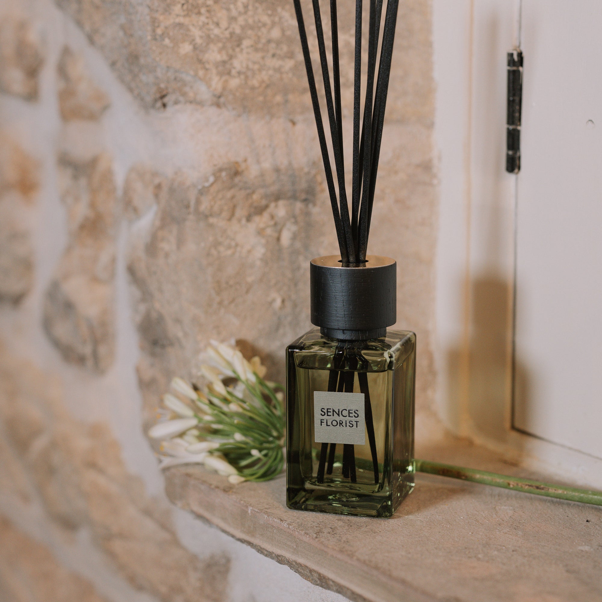 Green florist Sences mini reed diffuser on stone windowsill.