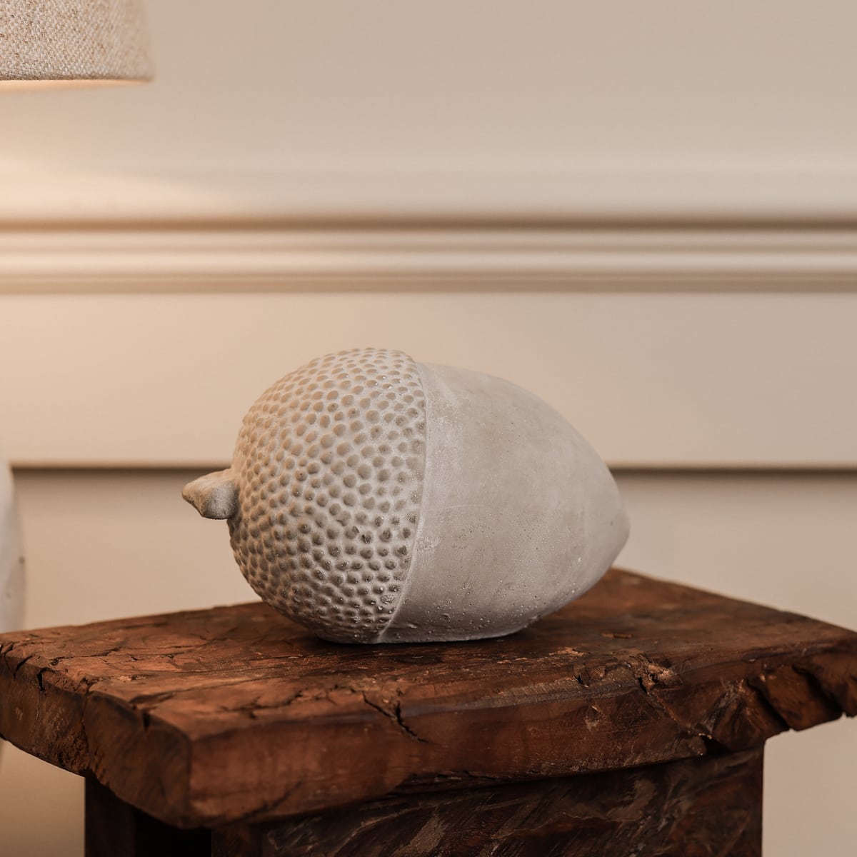 Cement acorn ornament on wooden stool.