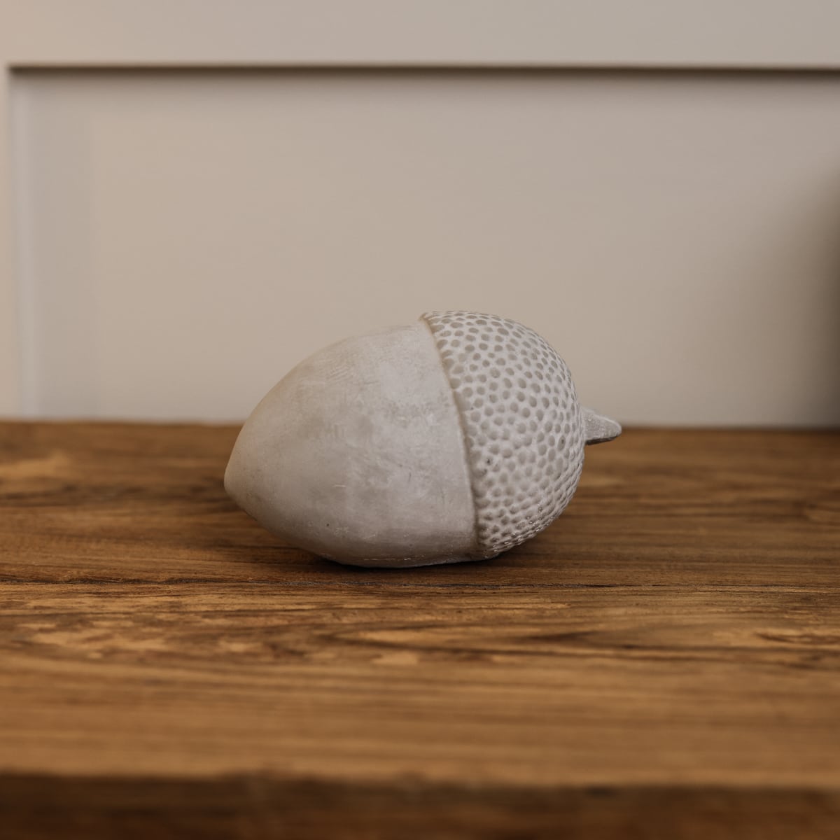 Cement acorn ornament on wooden console.