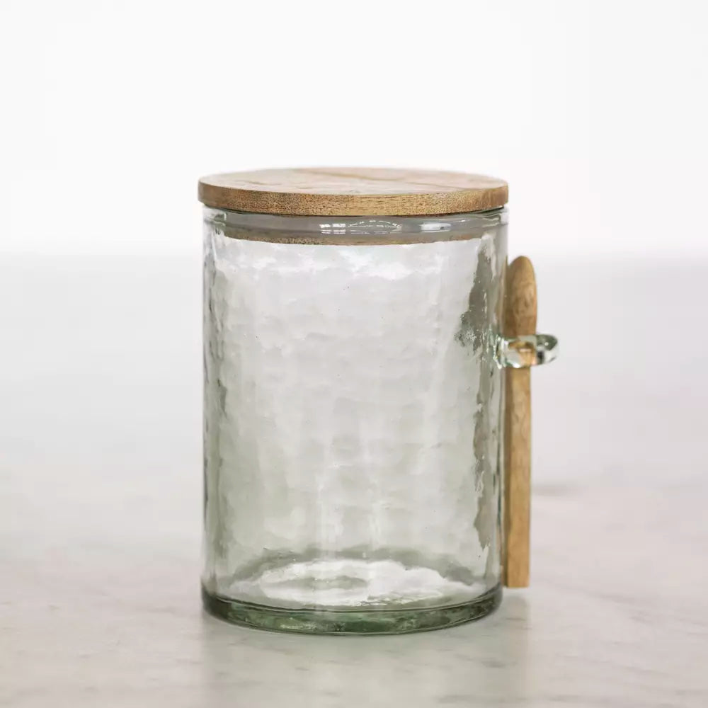 Hammered glass storage jar with wooden lid and small spoon.