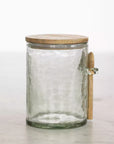 Hammered glass storage jar with wooden lid and small spoon.