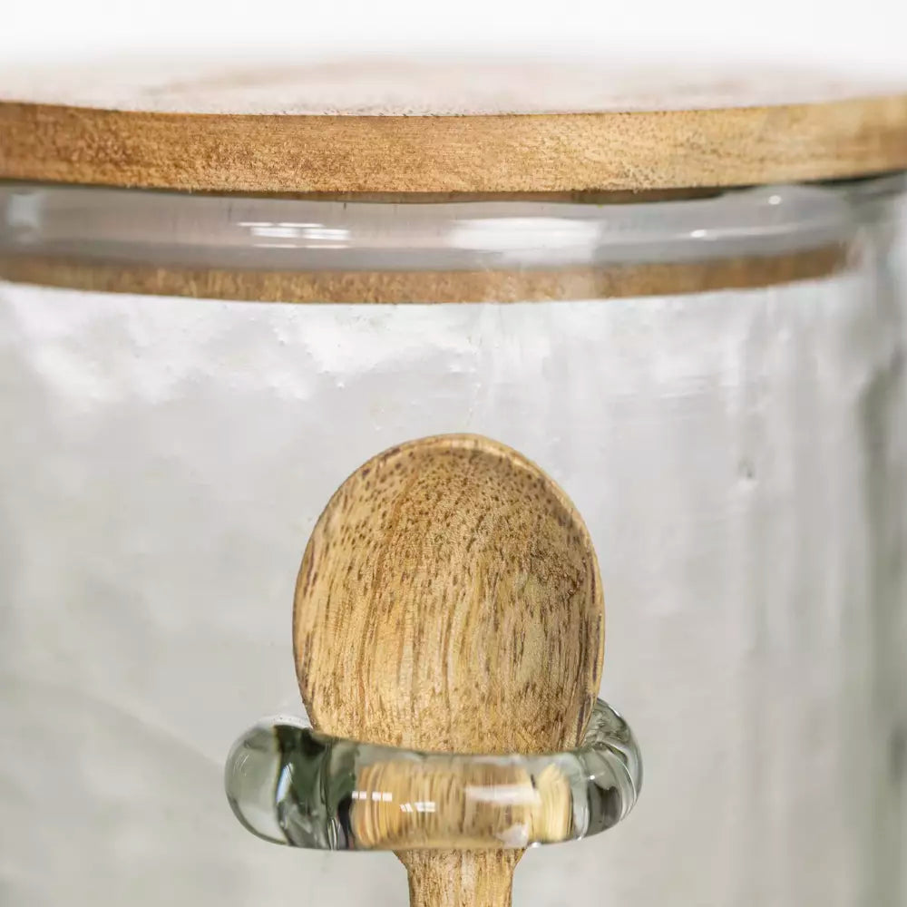 Close up of small wooden spoon on hammered glass jar.