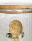 Close up of small wooden spoon on hammered glass jar.