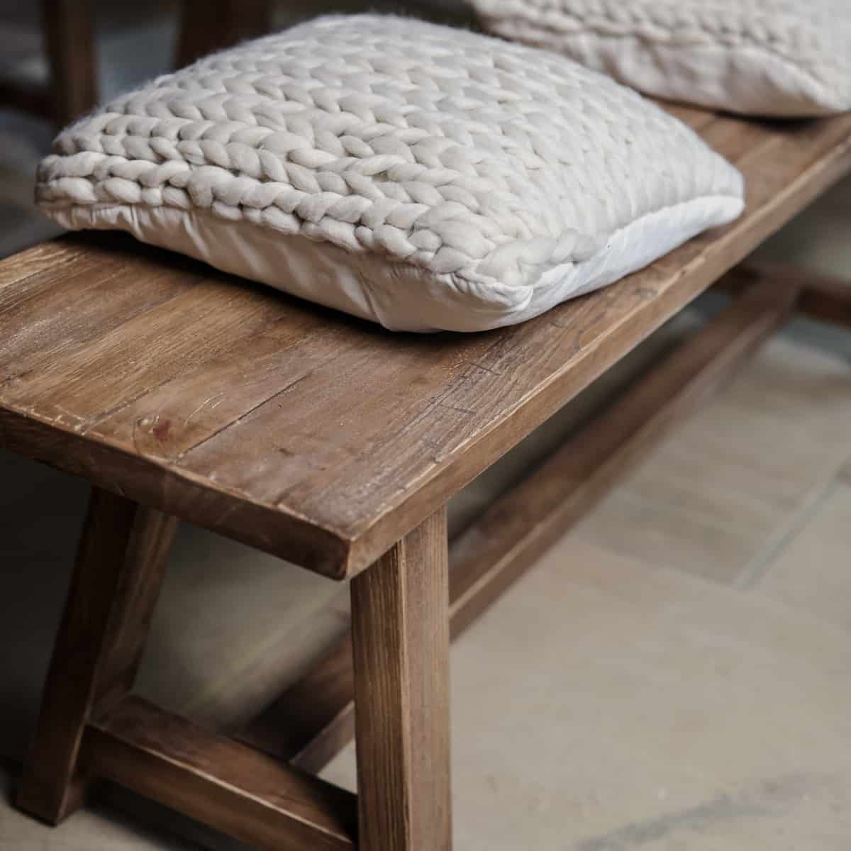 Oak bench with cream cushion close up.