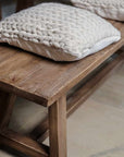 Oak bench with cream cushion close up.