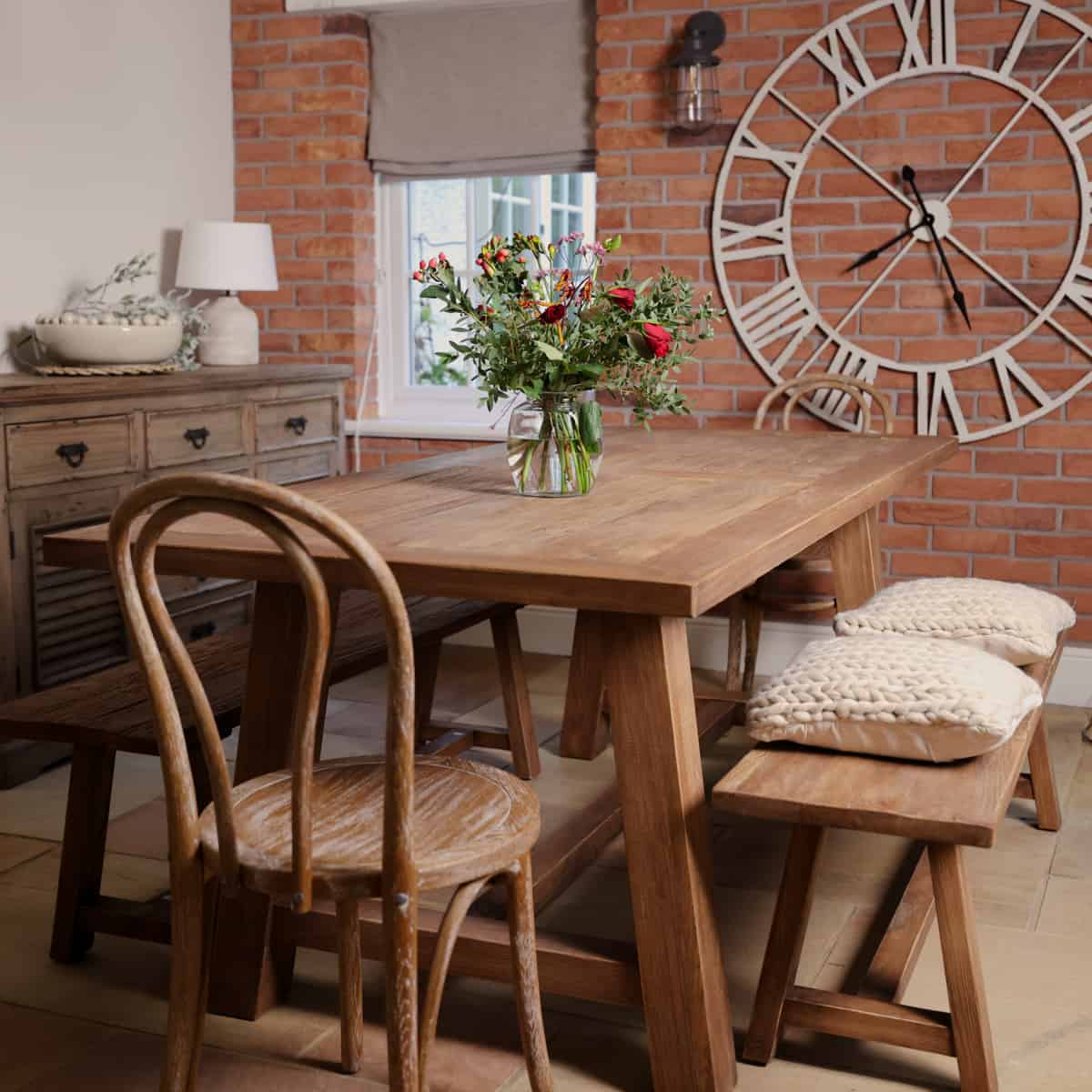 Elm dining table with flowers in centre, with bench and chairs.