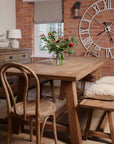 Elm dining table with flowers in centre, with bench and chairs.