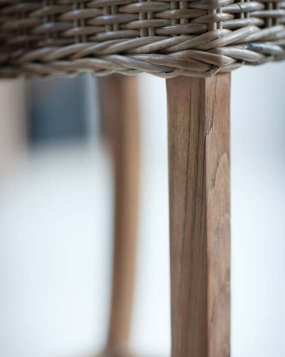 Close up of natural grain on teak legs of farmhouse woven bar stool with back.