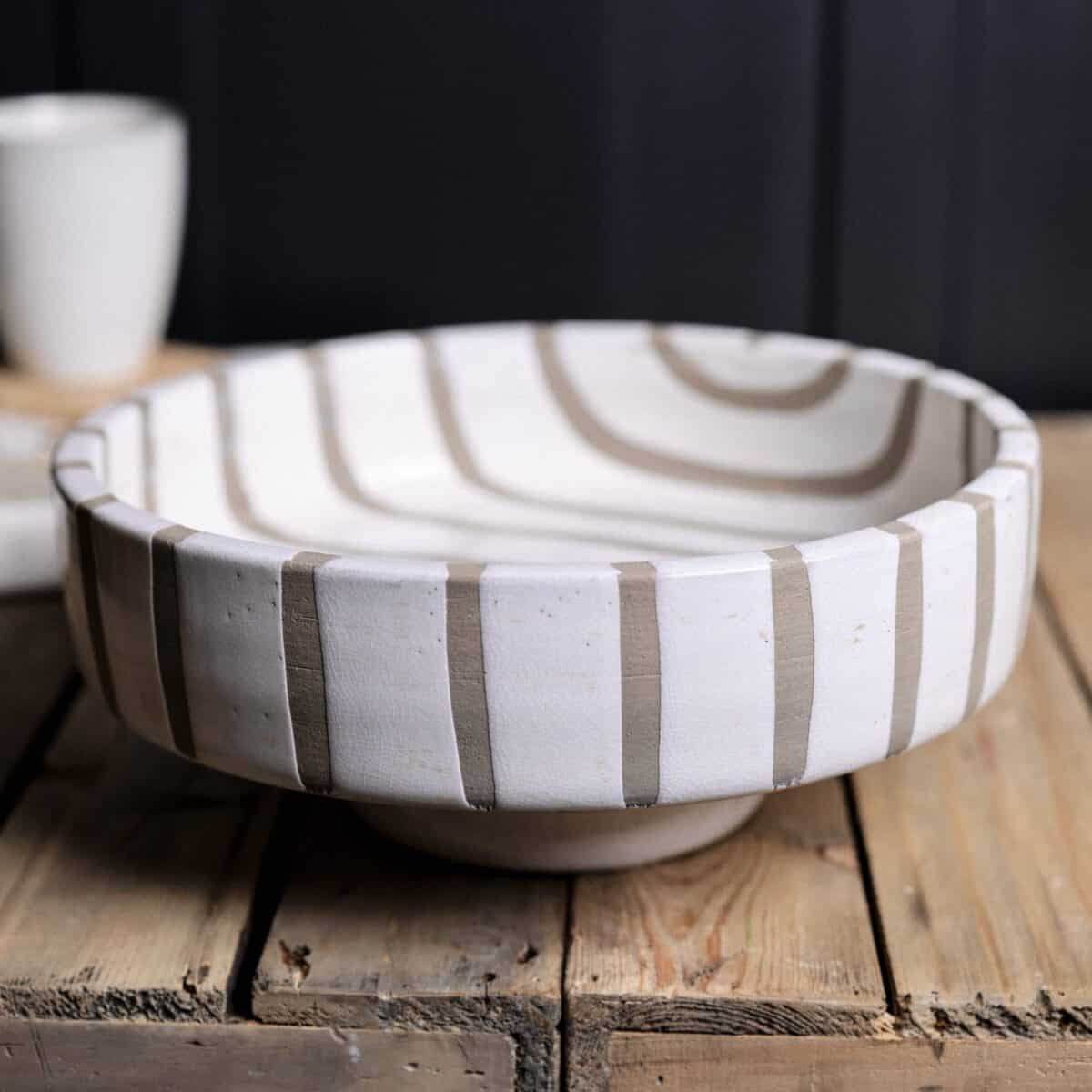 Striped terracotta ceramic fruit bowl on wooden console. 