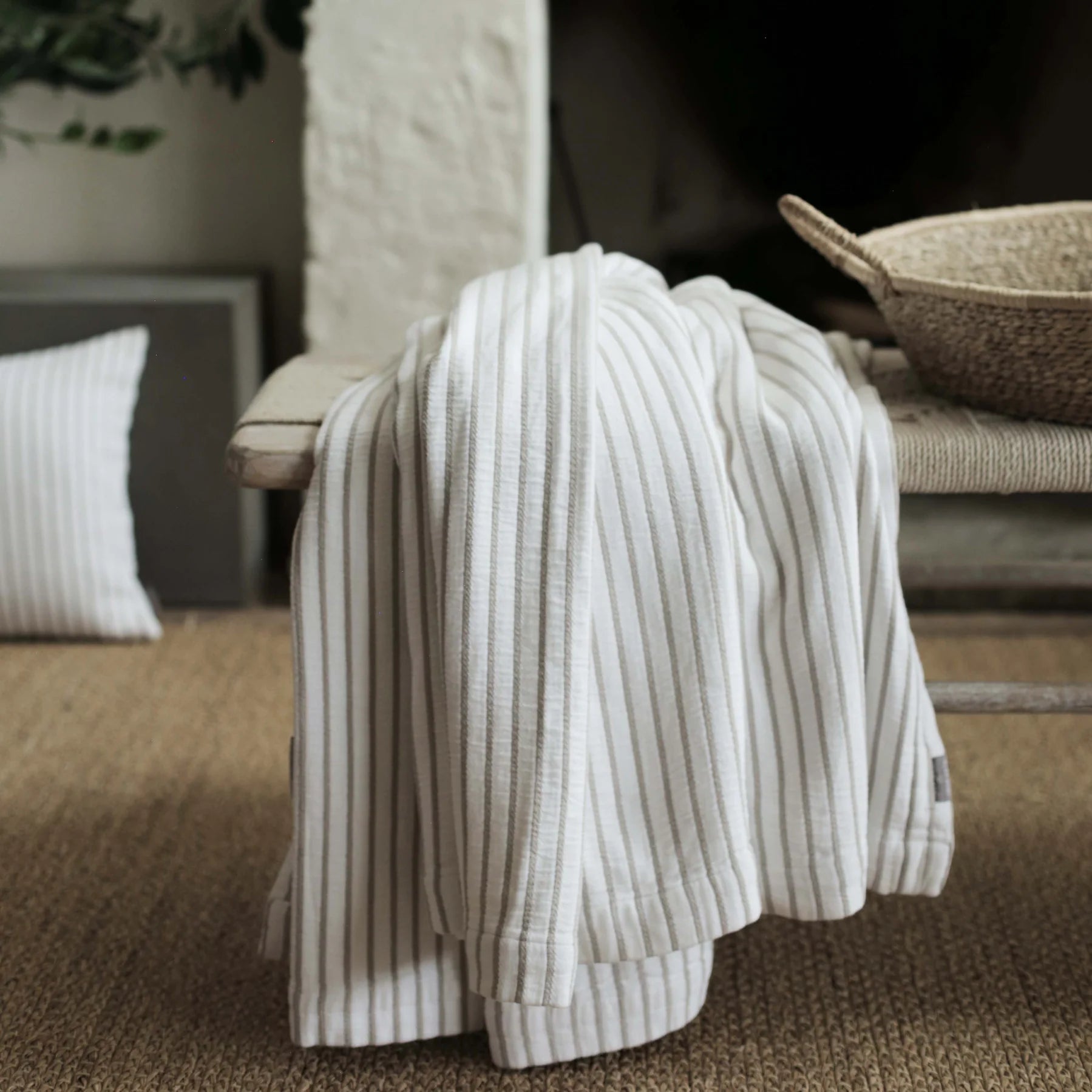 a Striped Cotton Throw Blanket draped over a woven coffee table with basket.