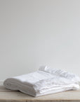 Textured White Bedspread folded neatly on a wooden table.