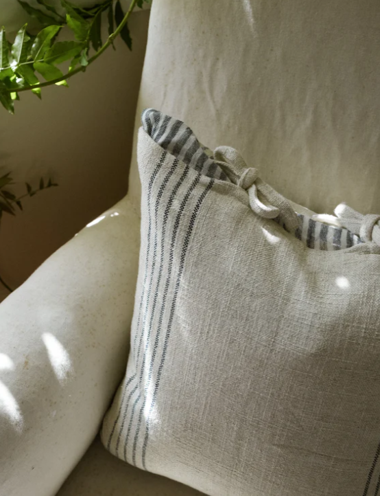 Close up of cream and blue striped cushion with bow tie detailing.