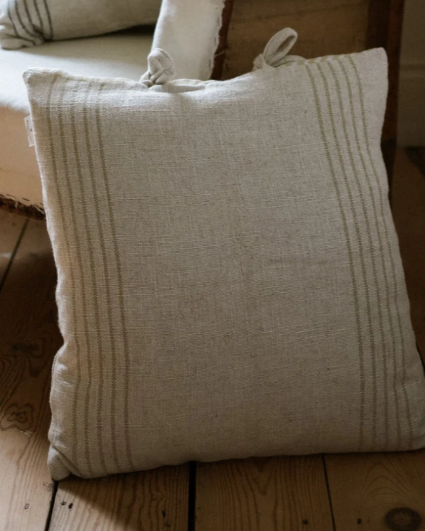 Close up of striped cream cushion leaning on wooden armchair.