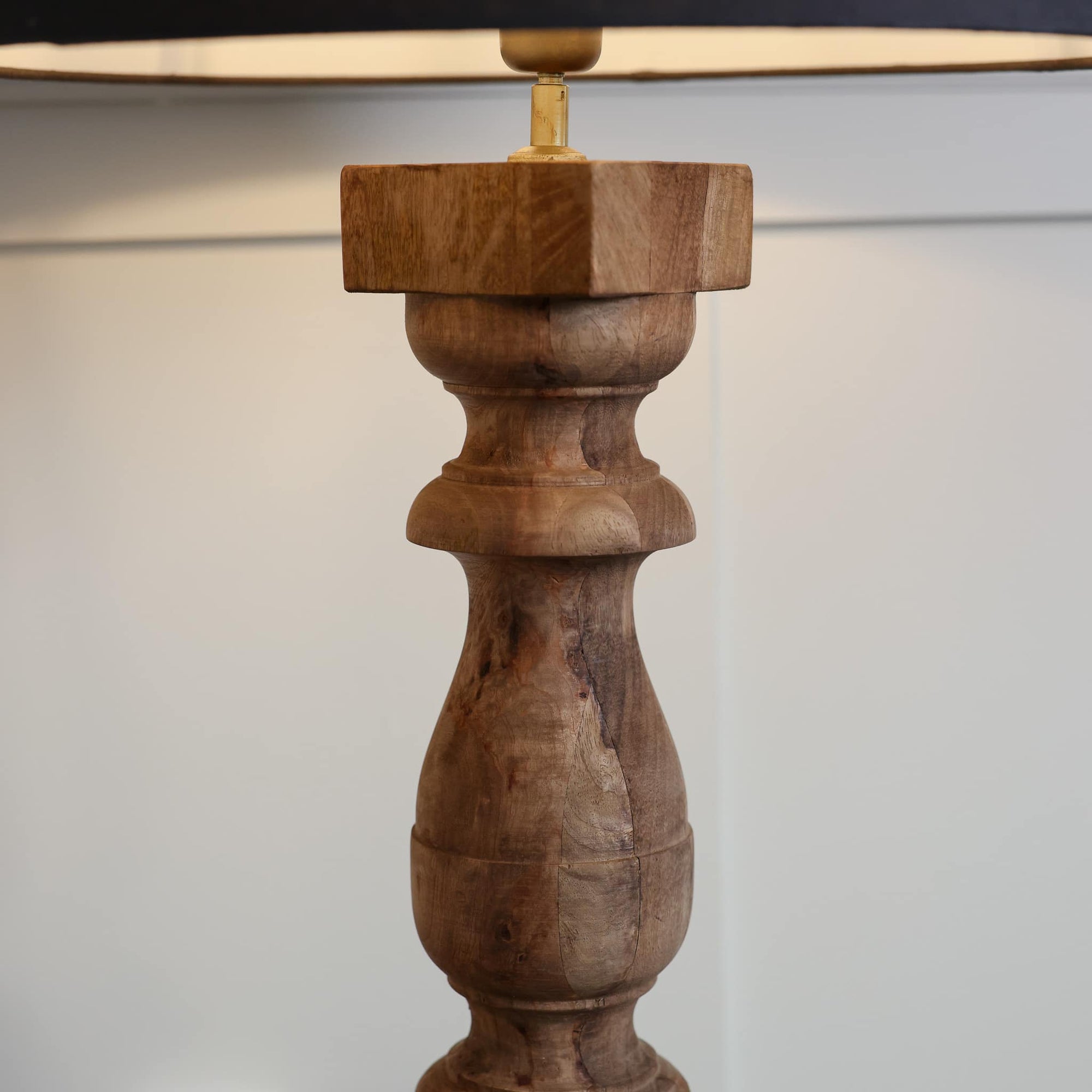Close up of curved wooden lamp base with square top.