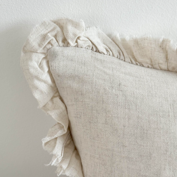 Close up of ruffled edge on sand coloured bolster cushion.