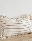 Brown and cream ruffle rectangle linen cushion on wooden surface.