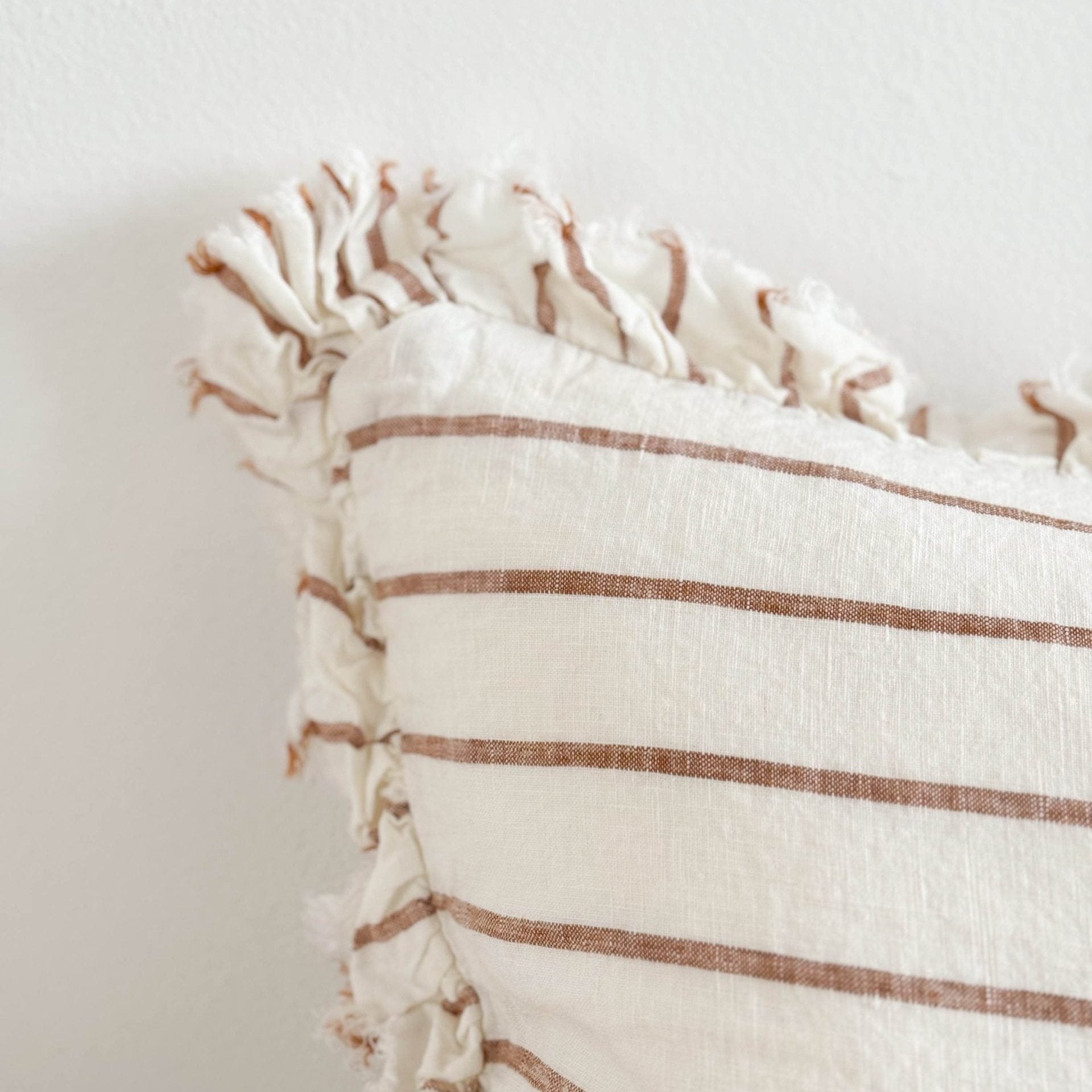 Close up of cream and brown striped ruffle linen cushion.