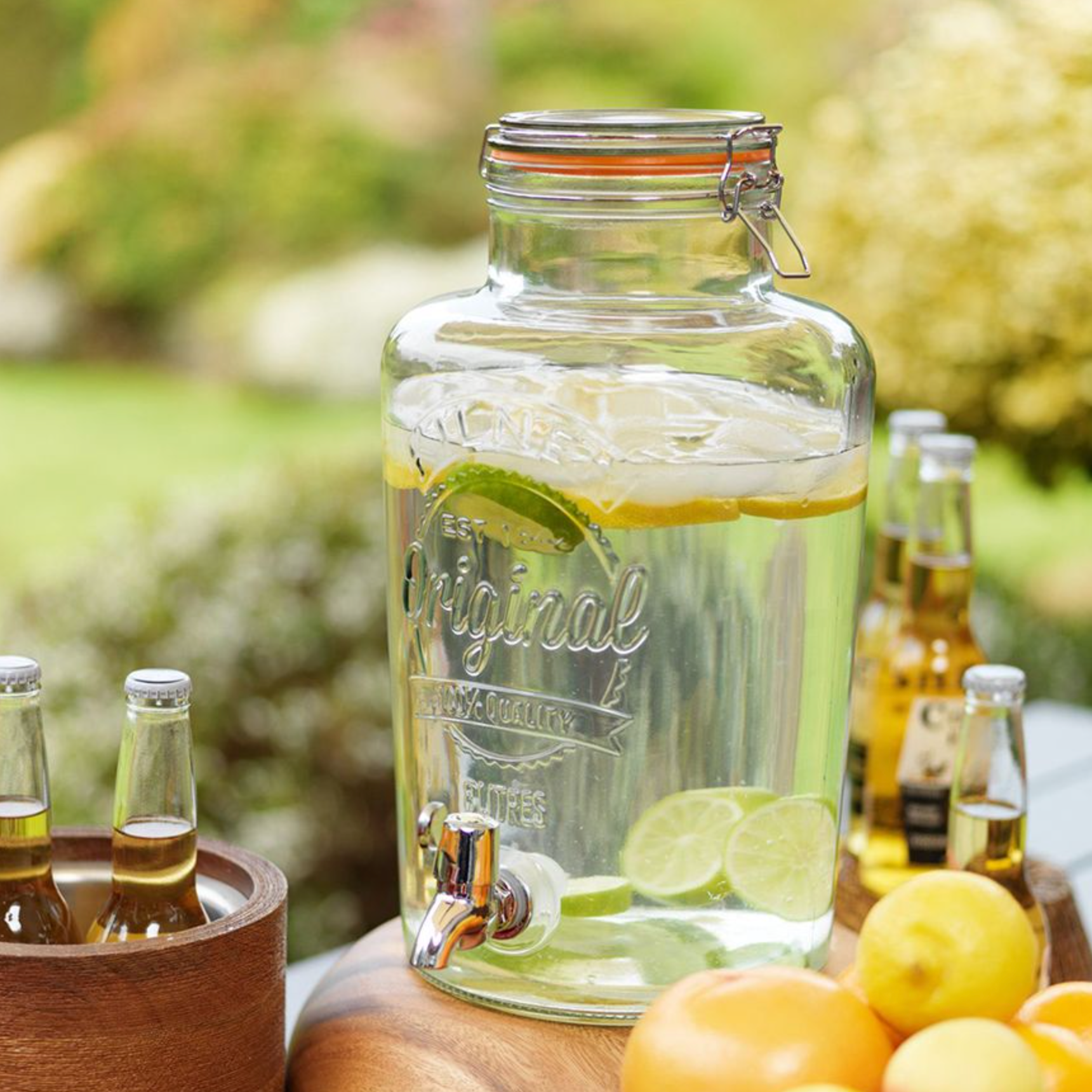 kilner drinks dispenser with lemons and limes in a garden setting.