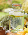 kilner drinks dispenser with lemons and limes in a garden setting.