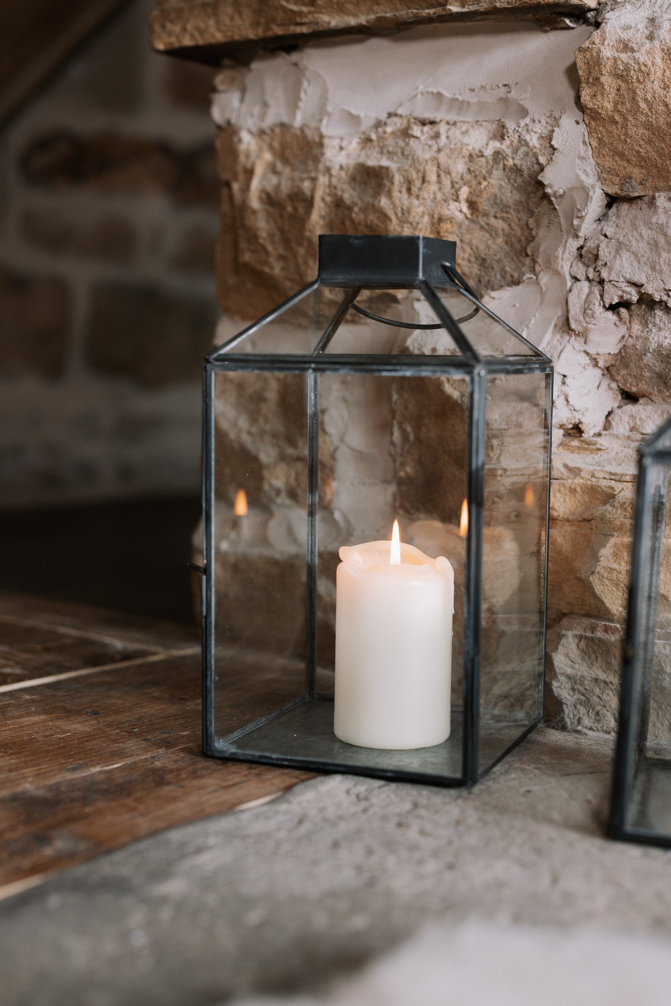 Set of two black and Glass Lanterns on stone hearth.