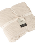 Natural cream crinkle cotton throw folded up and wrapped in a bow.