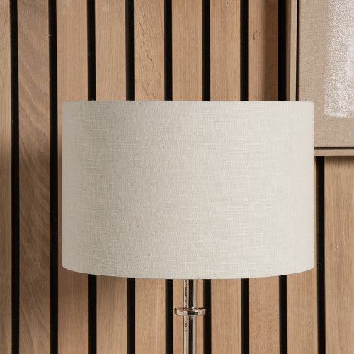 Large cream linen lamp shade in front of panel wall.