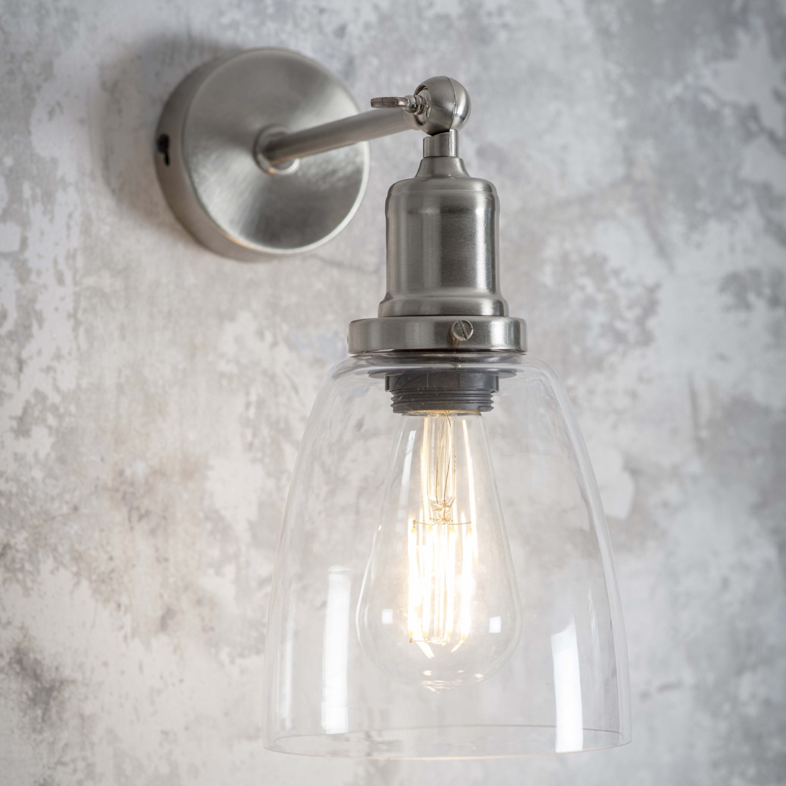 silver wall light with glass shade, close up.