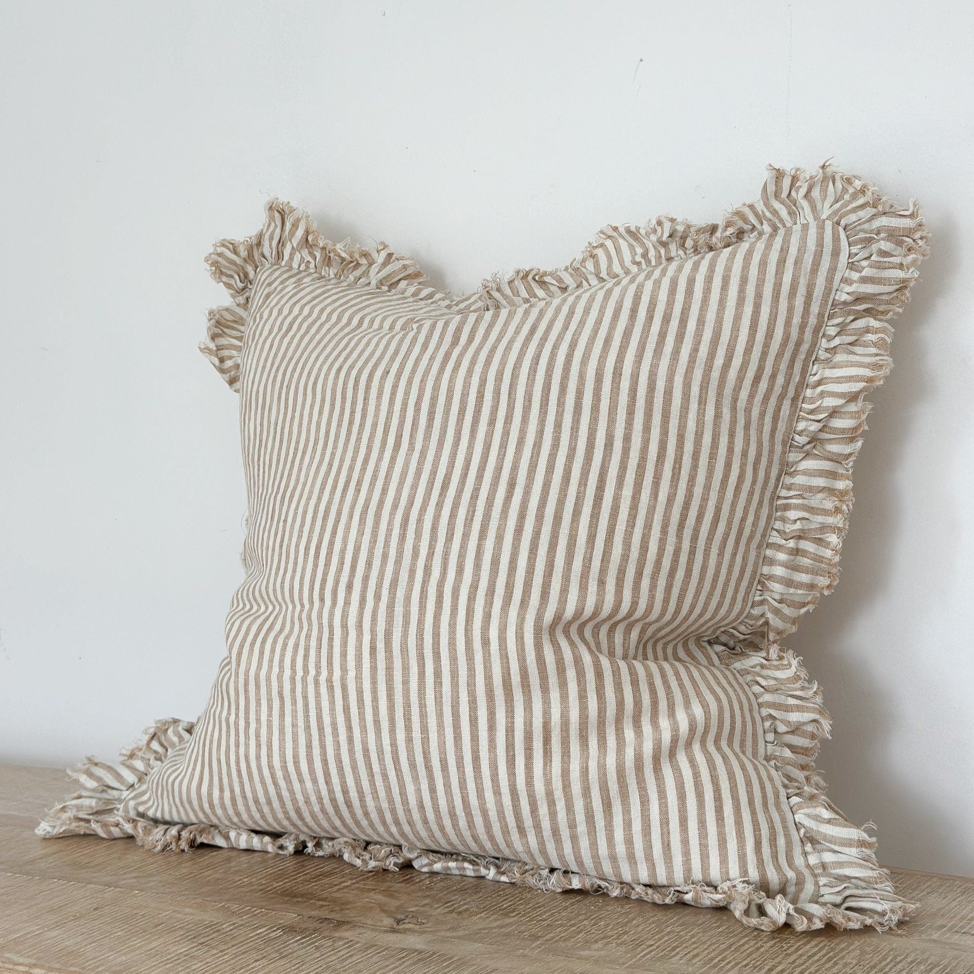 Light brown striped cushion with ruffled frayed edge.