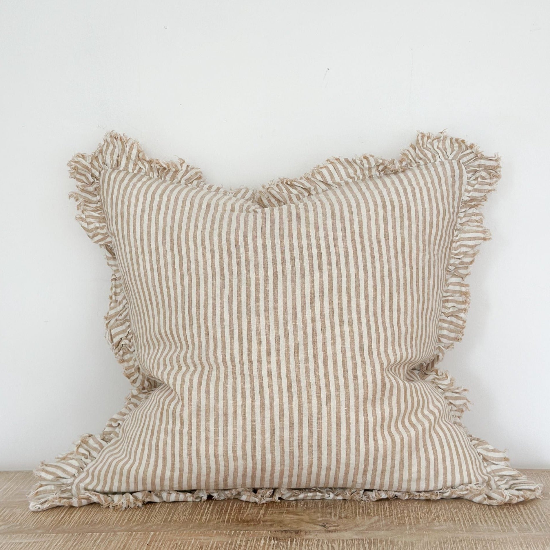 Light brown striped cushion with ruffled frayed edge.