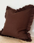 Large chocolate ruffle linen cushion on wooden surface.