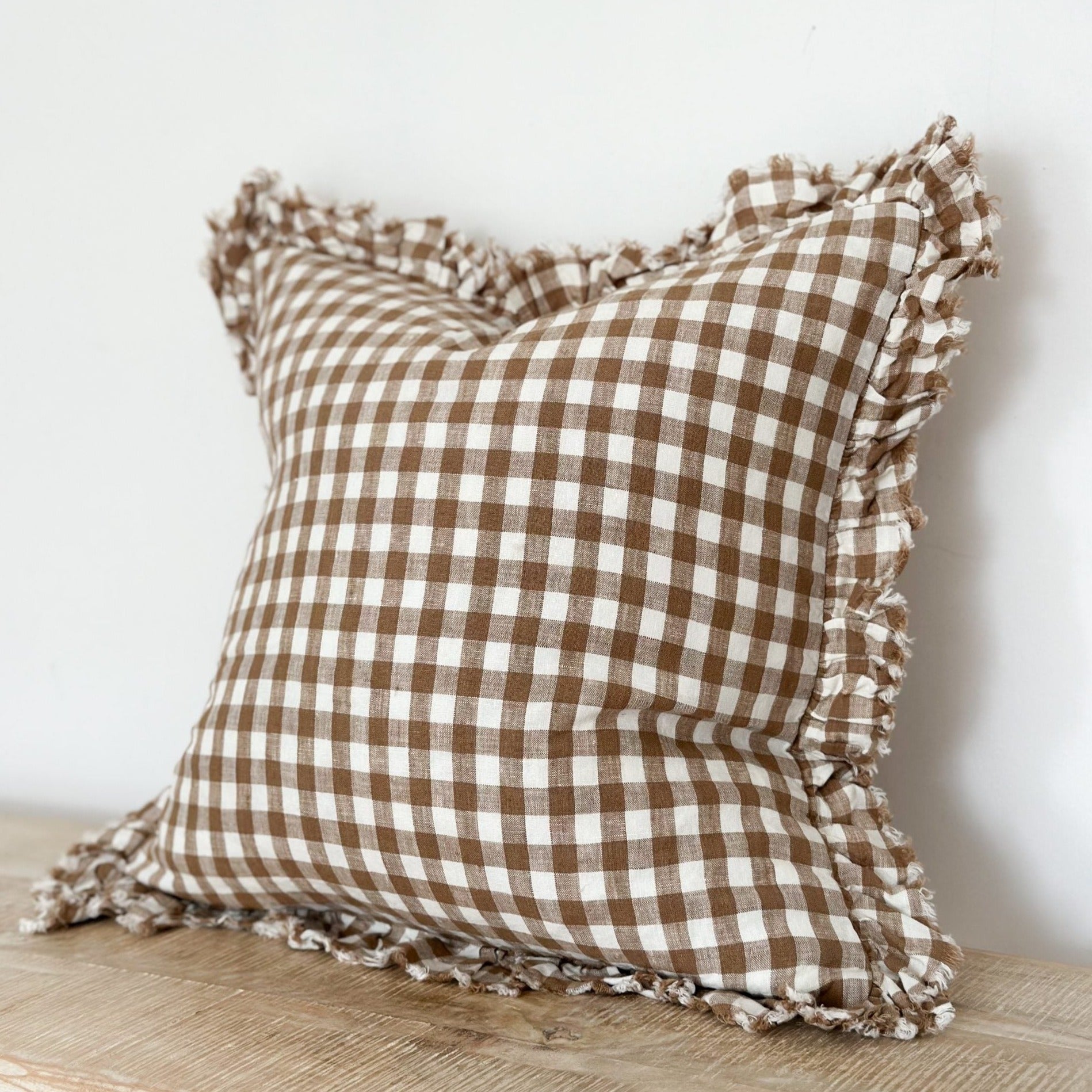 Brown gingham linen cushion with ruffled edge.