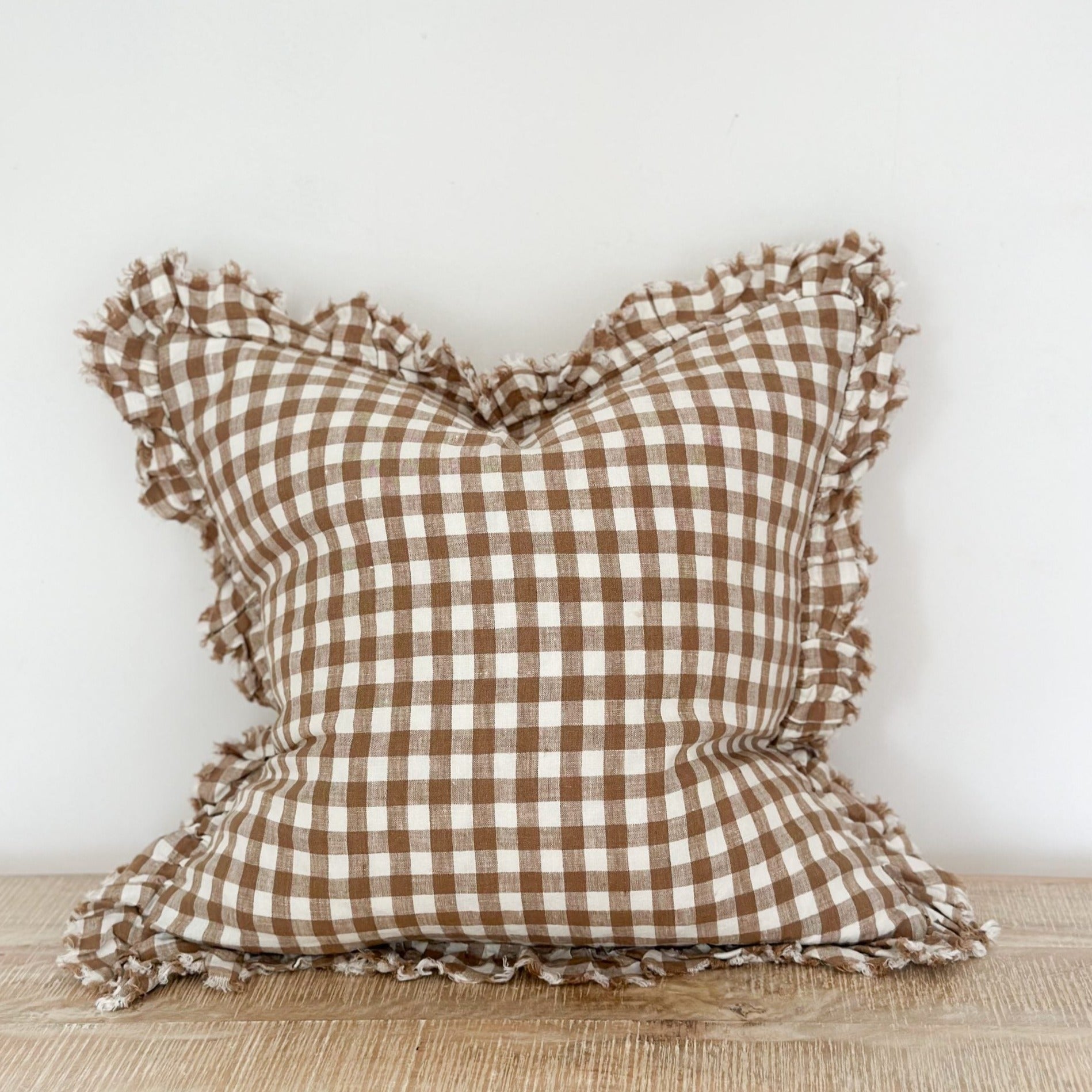 Brown gingham linen cushion with ruffled edge.