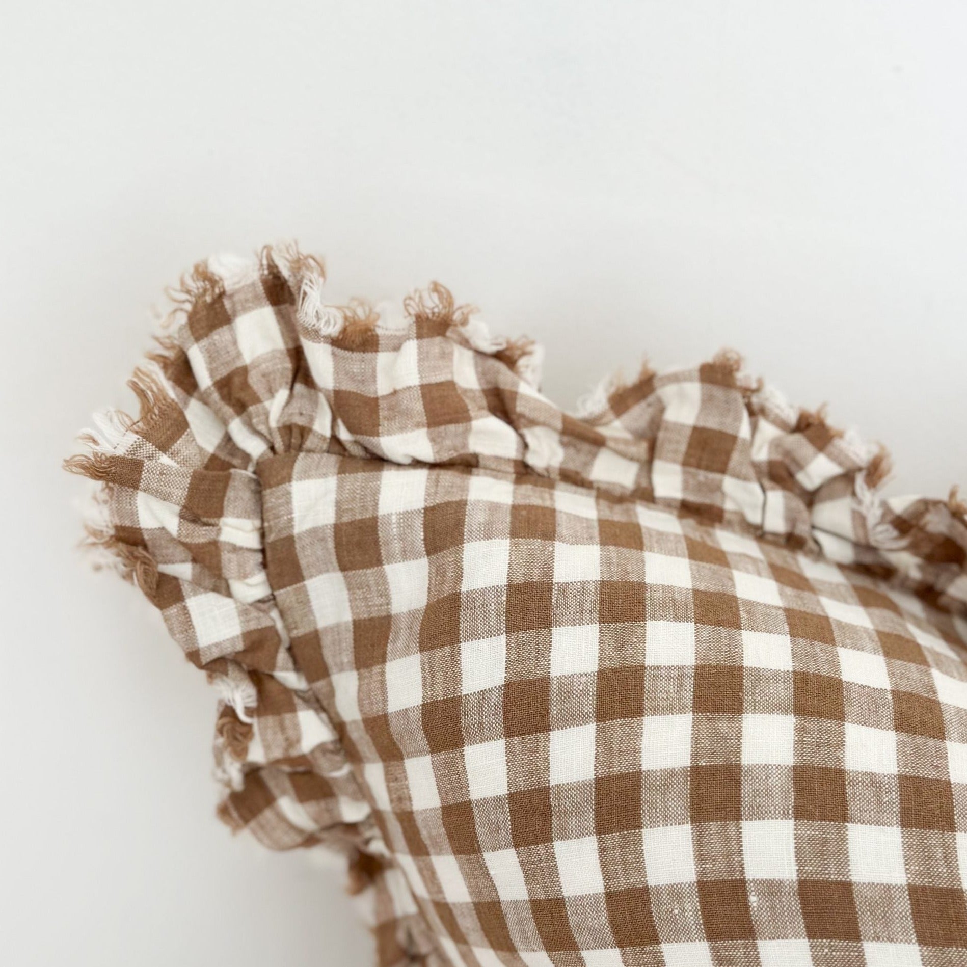 Close up of ruffled edge on brown gingham linen cushion.