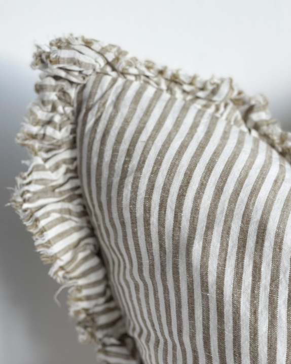 Close up of ruffled edge of olive and natural striped cushion.