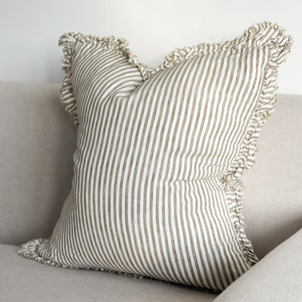 Olive and natural striped cushion with ruffled edge on a sofa.