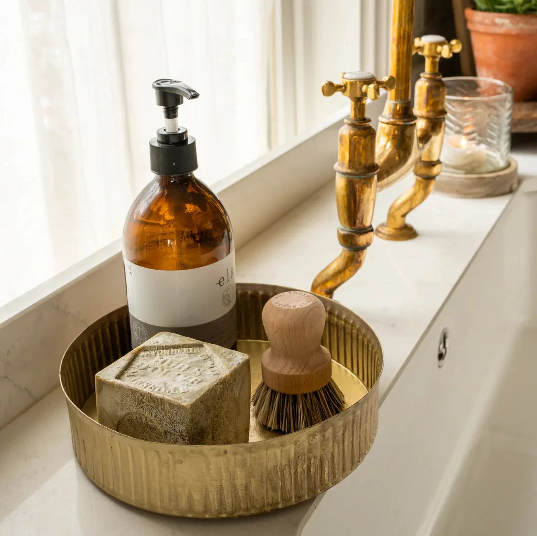 Brass metal tray with soaps inside, next to kitchen.