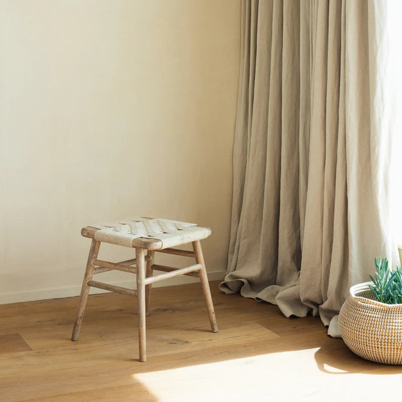 Lulworth Rustic Wooden Stool against a neutral wall with linen curtains.