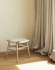 Lulworth Rustic Wooden Stool against a neutral wall with linen curtains.