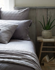 A rustic bedroom with lilac bedding, wooden cladded walls and the Lulworth Rustic Wooden Stool as a bedside table. 