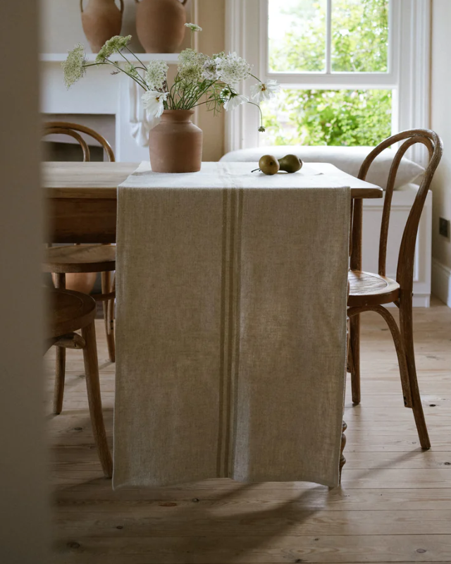 Cream linen table runner draped across wooden dining table.