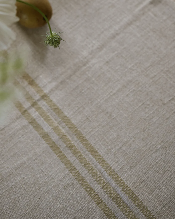 Close up of stripe detail on cream linen table runner.